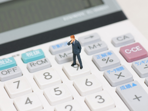電卓の上にサラリーマンの人形が立っている