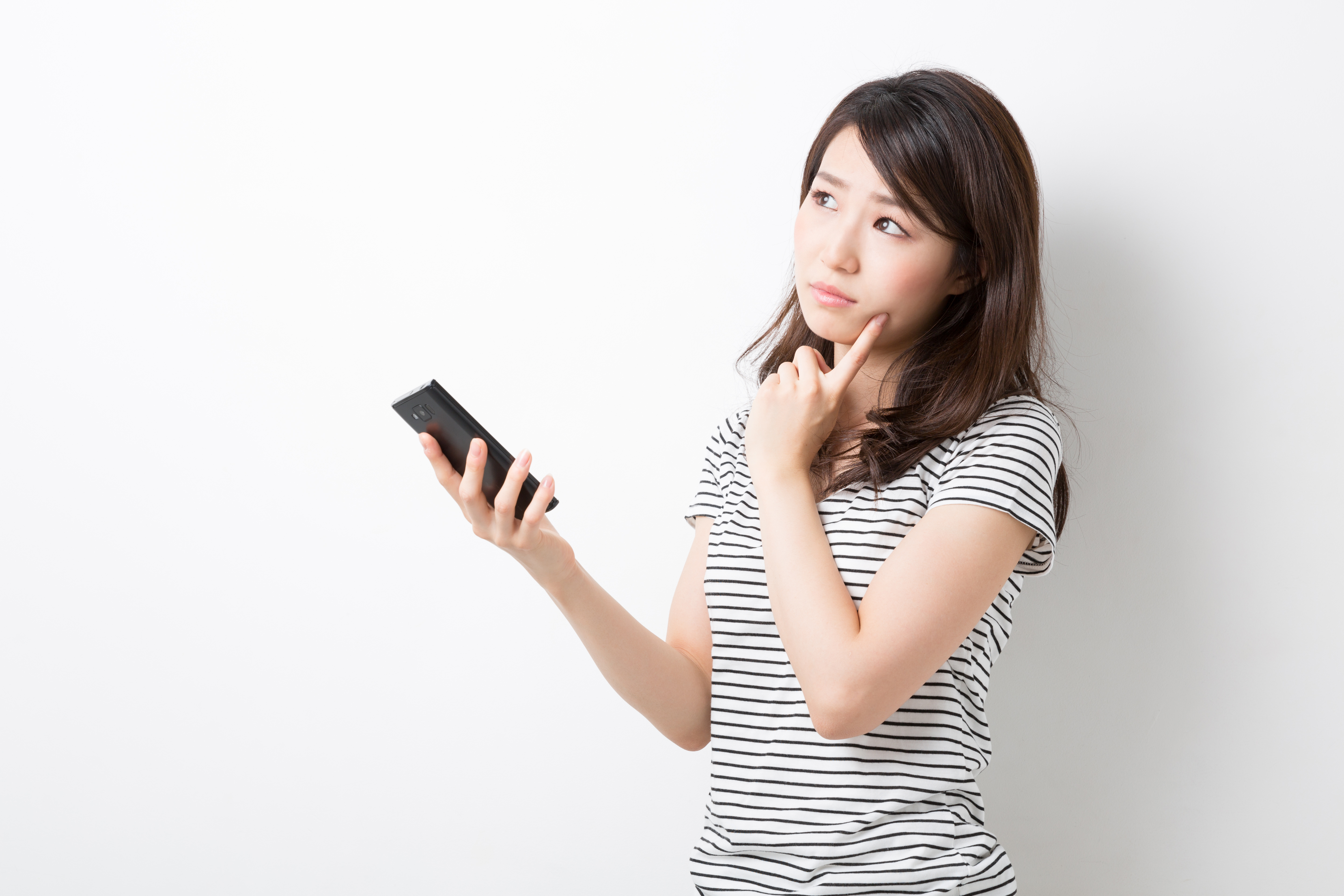 スマートフォンを見ながら悩む女性