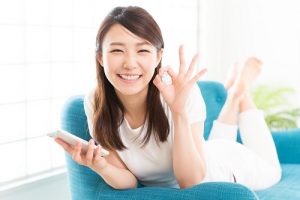 ソファに横になりokマークをする笑顔の女性